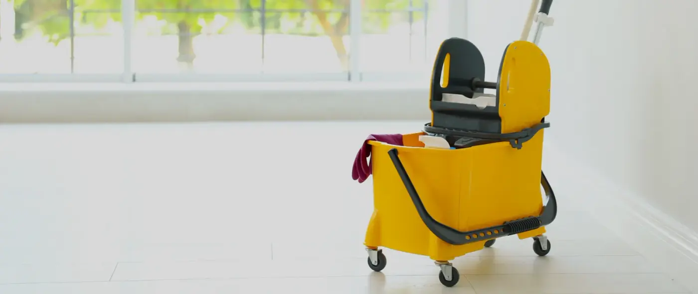 A yellow janitorial mop bucket with wiping cloths