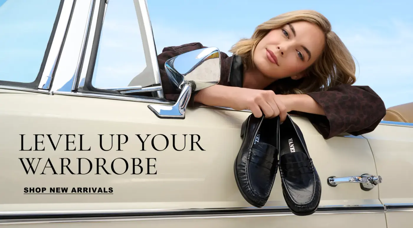 A woman in a vintage car holding a pair of loafers